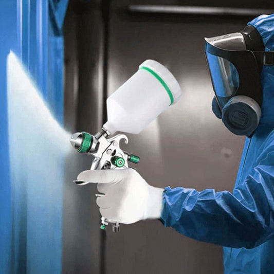 Person in protective gear using a spray gun with a blurred background